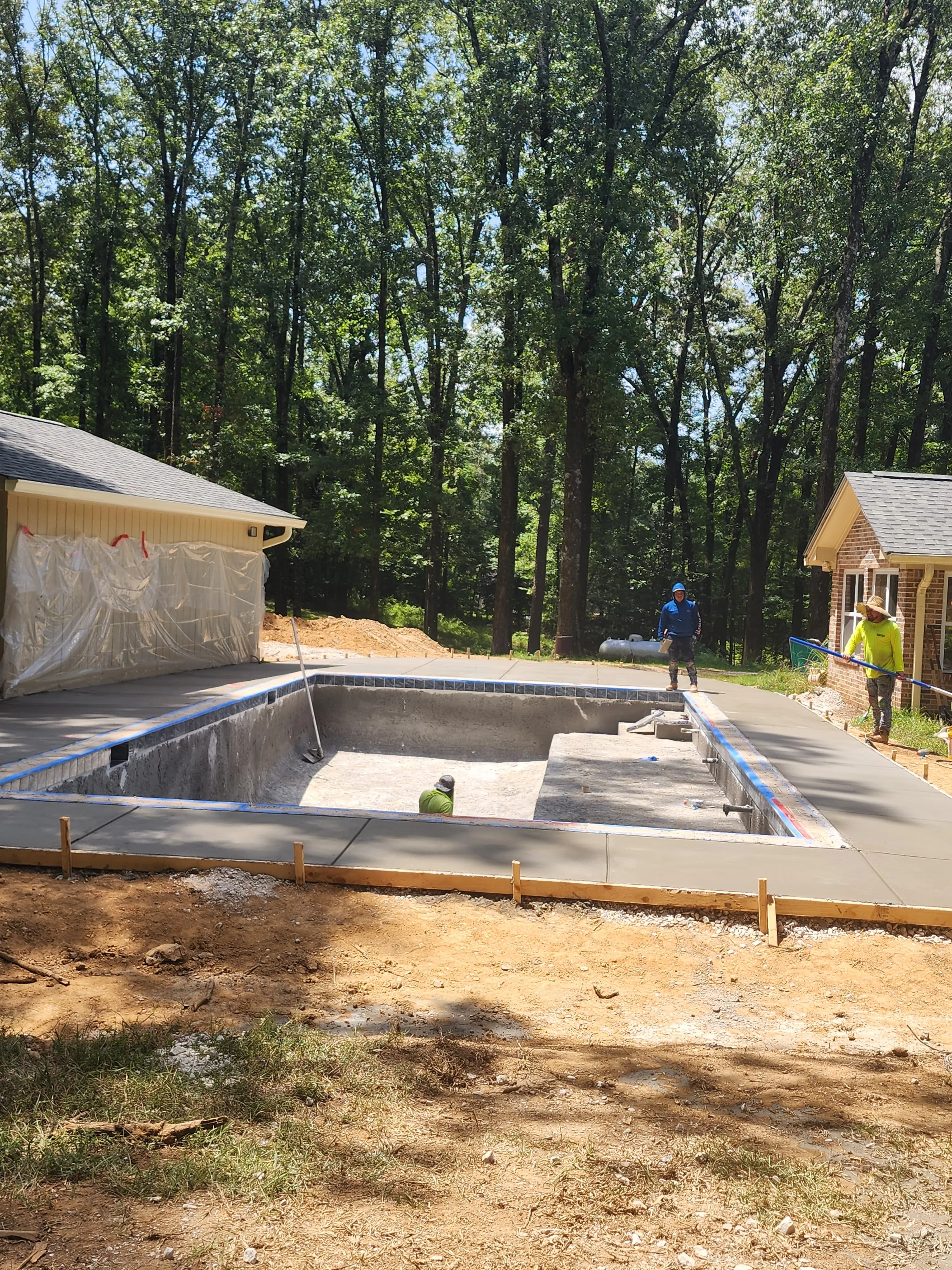 Crew finishing a concrete pool deck pour, Pearl, MS