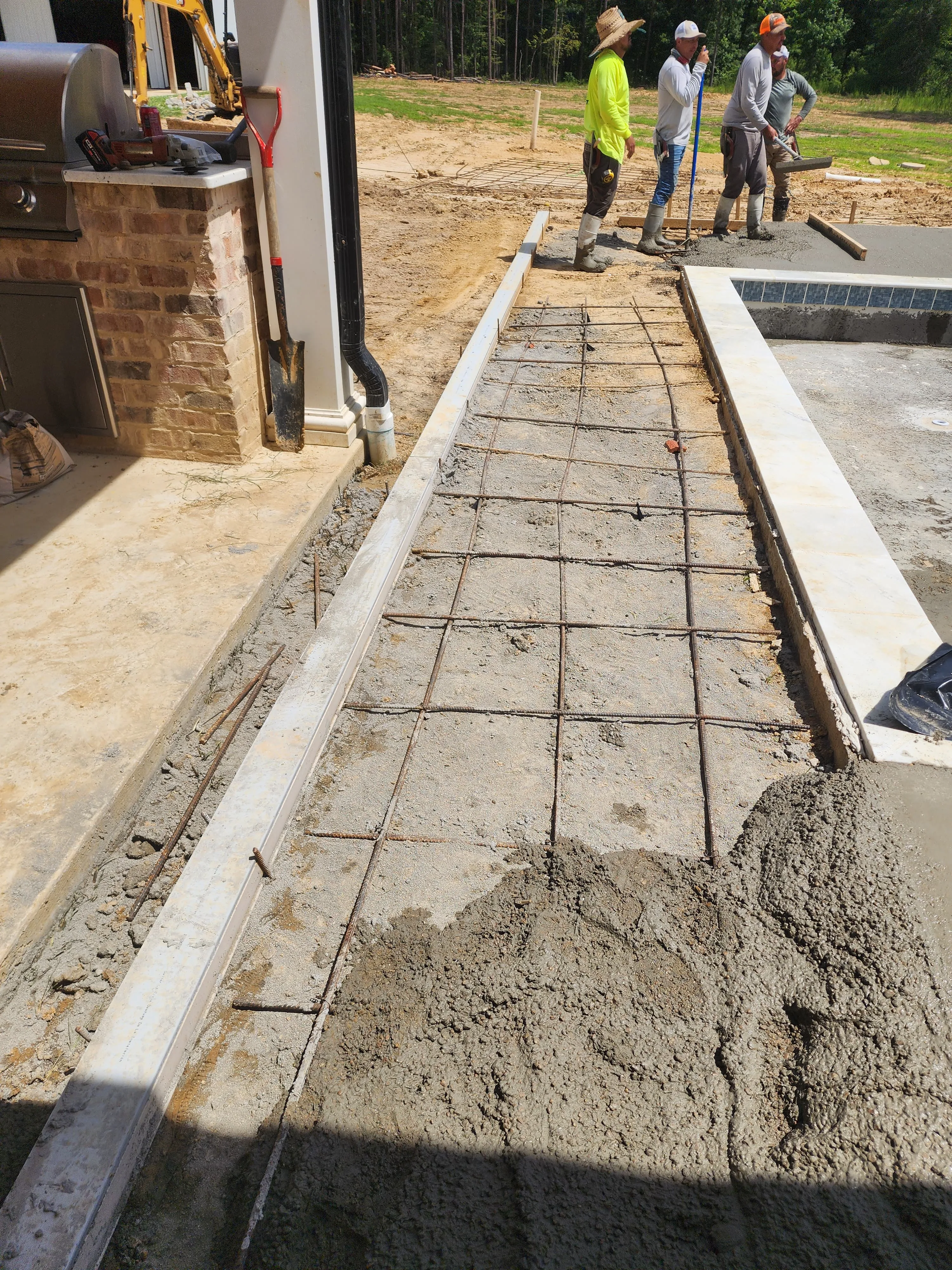 Crew finishing a concrete pour beside a pool, Pearl, MS